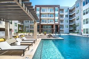 Fort Worth apartment for rent - A large swimming pool with sun loungers and a building in the background.
