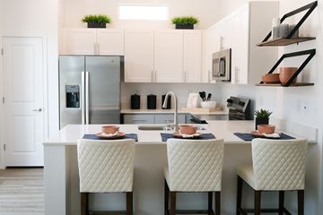 Hoschton apartment for rent - A kitchen with a table and chairs in the foreground and a refrigerator in the background.