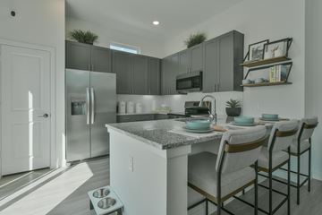Liberty Hill apartment for rent - A kitchen with a refrigerator, microwave, and a counter with chairs.