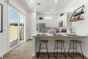 Glendale apartment for rent - A kitchen with white cabinets and a white island with three bar stools.