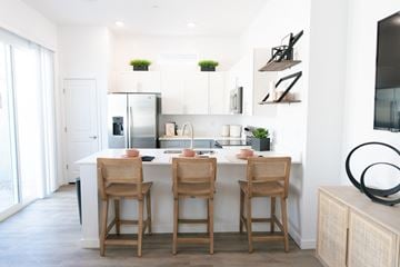 Phoenix apartment for rent - a kitchen with white cabinets and a white island with wooden chairs