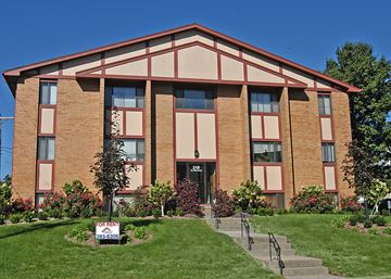 Omaha apartment for rent - the front of a brick building with a sign in the grass