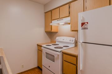 Omaha apartment for rent - a kitchen with white appliances and wooden cabinets and a refrigerator
