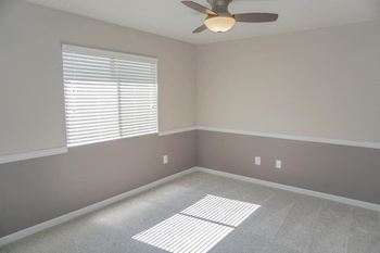 An empty room with a ceiling fan and a window