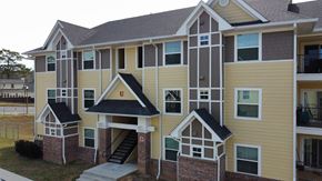 Pensacola apartment for rent - an apartment building with yellow siding and a staircase at The Fountains Apartments, Pensacola, 32514