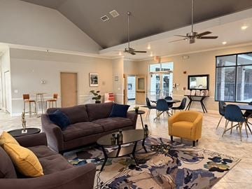 Gainesville apartment for rent - A living room with a brown couch, a yellow chair, and a rug with a floral pattern.