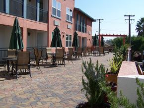 Santa Clara apartment for rent - A patio with chairs and umbrellas is in front of a pink building.