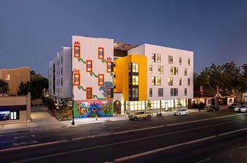San Jose apartment for rent - A building with a colorful mural on its side is illuminated at night.