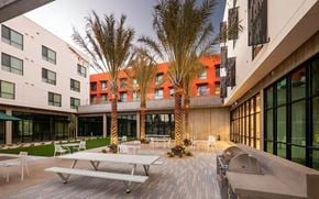 San Jose apartment for rent - A modern building with a courtyard and palm trees.