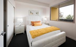 San Jose apartment for rent - A bedroom with a white bed and a yellow pillow.