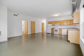 Minneapolis apartment for rent - the living room and kitchen of an empty apartment with white appliances and wood cabinets