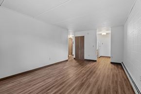 Anoka apartment for rent - the living room and hallway of an empty house with wood floors and white walls