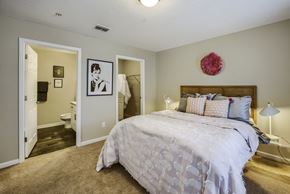 Columbus apartment for rent - a bedroom with a large bed and a bathroom in the background