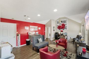 Valdosta apartment for rent - A living room with a red couch and a grey armchair.