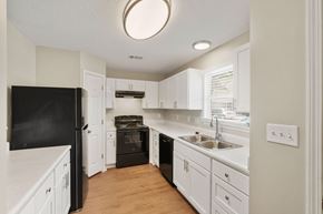 Valdosta apartment for rent - A kitchen with white cabinets and a black fridge.