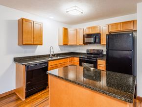 Bridgeport townhouse for rent - a kitchen with an island and black appliances and wooden cabinets
