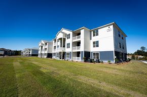 Brunswick apartment for rent - A large white building with a blue trim is surrounded by a grassy field.