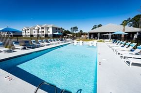 Brunswick apartment for rent - A large swimming pool with lounge chairs and umbrellas.