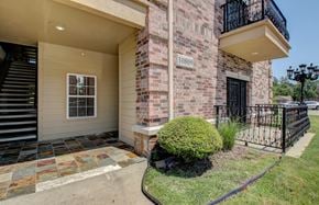 North Little Rock apartment for rent - A brick building with a black gate and a green bush in front.