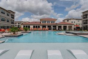 Houston apartment for rent - A large swimming pool in front of a building with a red roof.