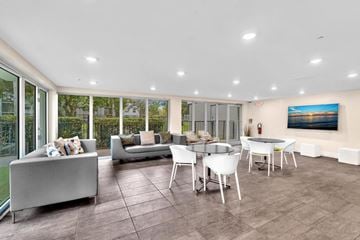 Plantation apartment for rent - A modern living room with a grey sofa, white chairs, and a painting on the wall.