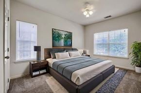 Macon apartment for rent - A bedroom with a large bed, a nightstand with a lamp, and a painting on the wall.