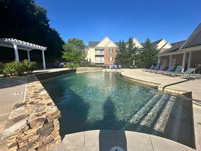 Forest apartment for rent - A pool with a stone wall and a building in the background.