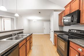 Forest apartment for rent - A kitchen with wooden cabinets and black appliances.