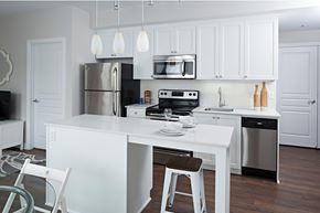 Ottawa apartment for rent - a white kitchen with a white island and stainless steel appliances