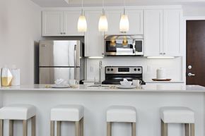 Ottawa apartment for rent - a kitchen with white cabinets and a bar with white stools