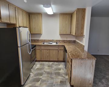 El Cajon apartment for rent - an empty kitchen with granite counter tops and wooden cabinets