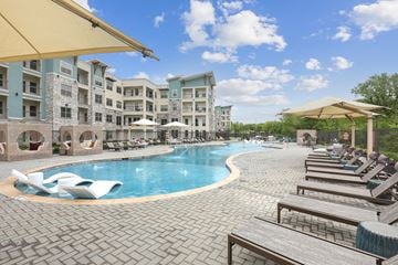 Olathe apartment for rent - A large outdoor swimming pool surrounded by sun loungers and umbrellas.