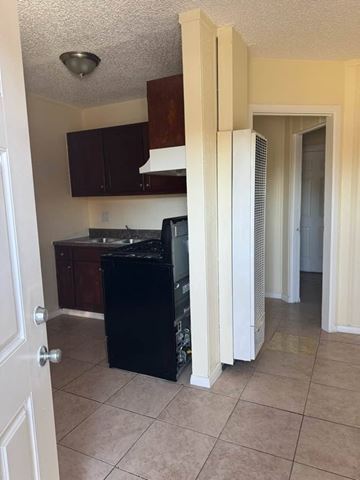 Los Angeles apartment for rent - A kitchen with a black fridge and white cabinets.