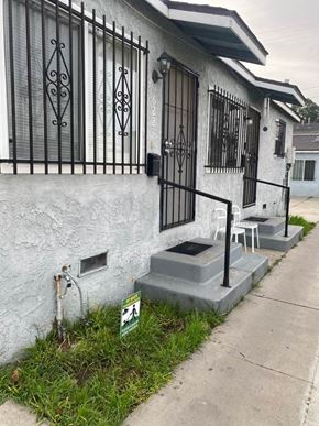 Los Angeles apartment for rent - A white house with a black iron gate and a green lawn in front.