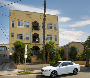 Los Angeles apartment for rent - A white car is parked in front of a yellow building with a no parking sign.