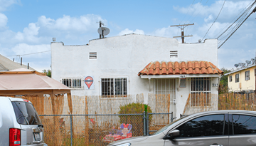 Los Angeles apartment for rent - A white building with a red roof and a sign on the fence.