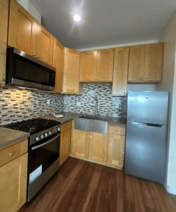 Los Angeles apartment for rent - A kitchen with wooden cabinets and a black stove top oven.
