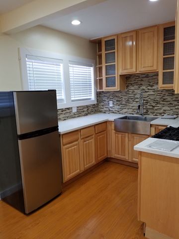Los Angeles apartment for rent - A kitchen with wooden cabinets and a black fridge.