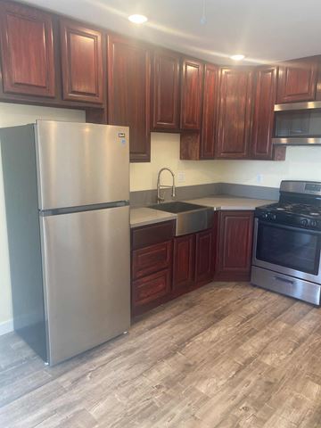 Compton apartment for rent - A kitchen with a stainless steel refrigerator and wooden cabinets.