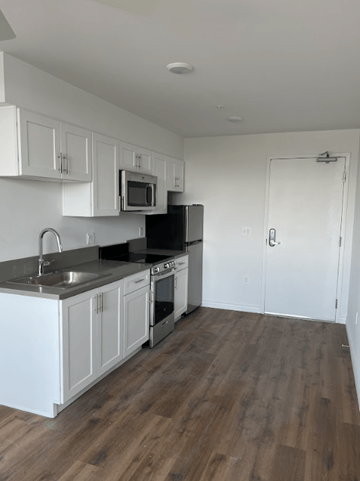 Los Angeles apartment for rent - A kitchen with white cabinets and a black stove top oven.