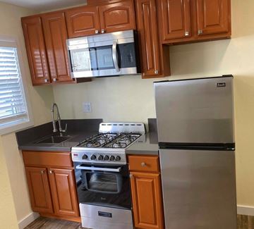 Long Beach apartment for rent - A kitchen with a stove, refrigerator, and cabinets.