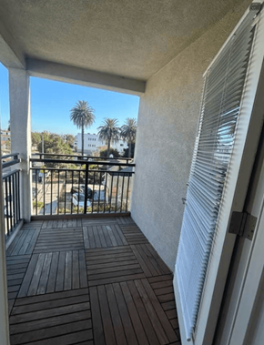 Los Angeles apartment for rent - A balcony with a view of a street and palm trees.