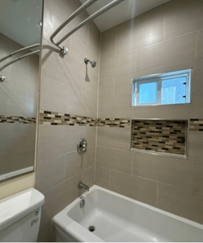 Los Angeles apartment for rent - A white bathtub is in a bathroom with a window above it.