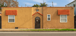 Long Beach apartment for rent - A tan building with a black door and two windows with red awnings.