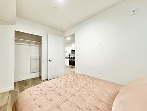 Los Angeles apartment for rent - A bedroom with a bed in the foreground and a kitchen in the background.