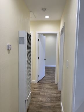 Los Angeles apartment for rent - A long hallway with a door on the right and a wall-mounted heater on the left.
