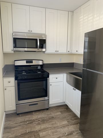 Compton apartment for rent - A kitchen with white cabinets and a black refrigerator.
