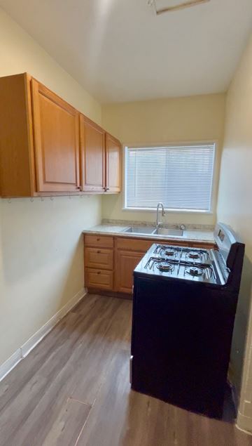 Los Angeles apartment for rent - A kitchen with wooden cabinets and a black stove top oven.