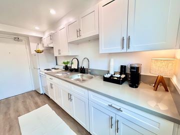 San Pedro apartment for rent - A kitchen with white cabinets and a light wood floor.