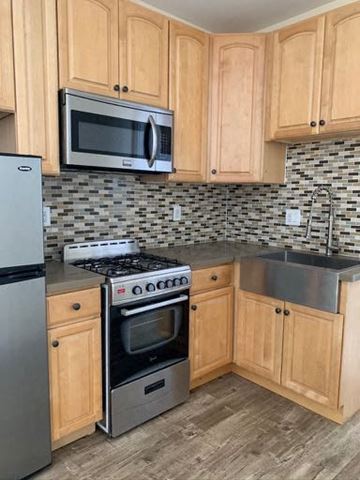Los Angeles apartment for rent - A kitchen with wooden cabinets and a black and white checkered backsplash.